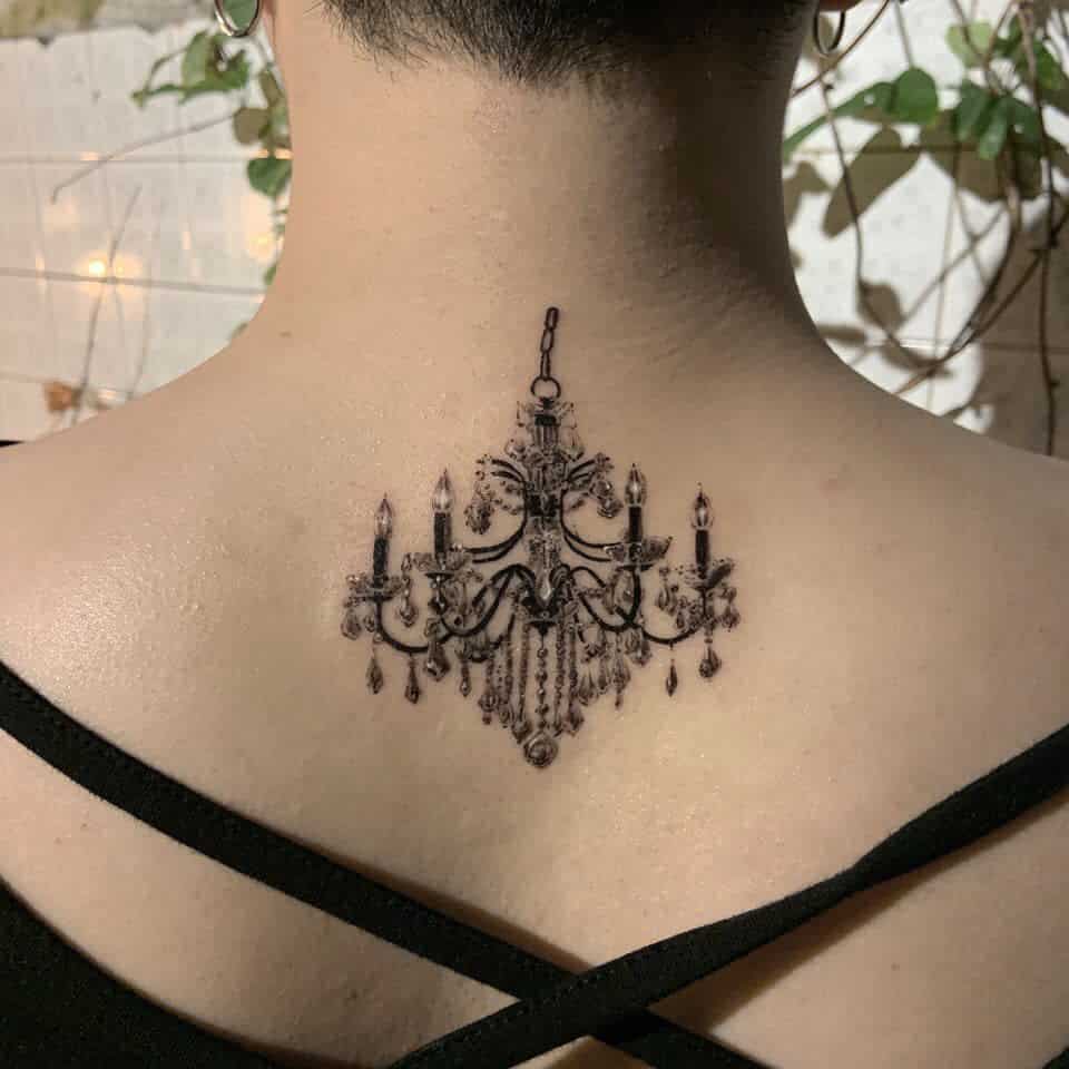 Black and grey tattoo of an ornate chandelier, with candle-like details and dangling beads