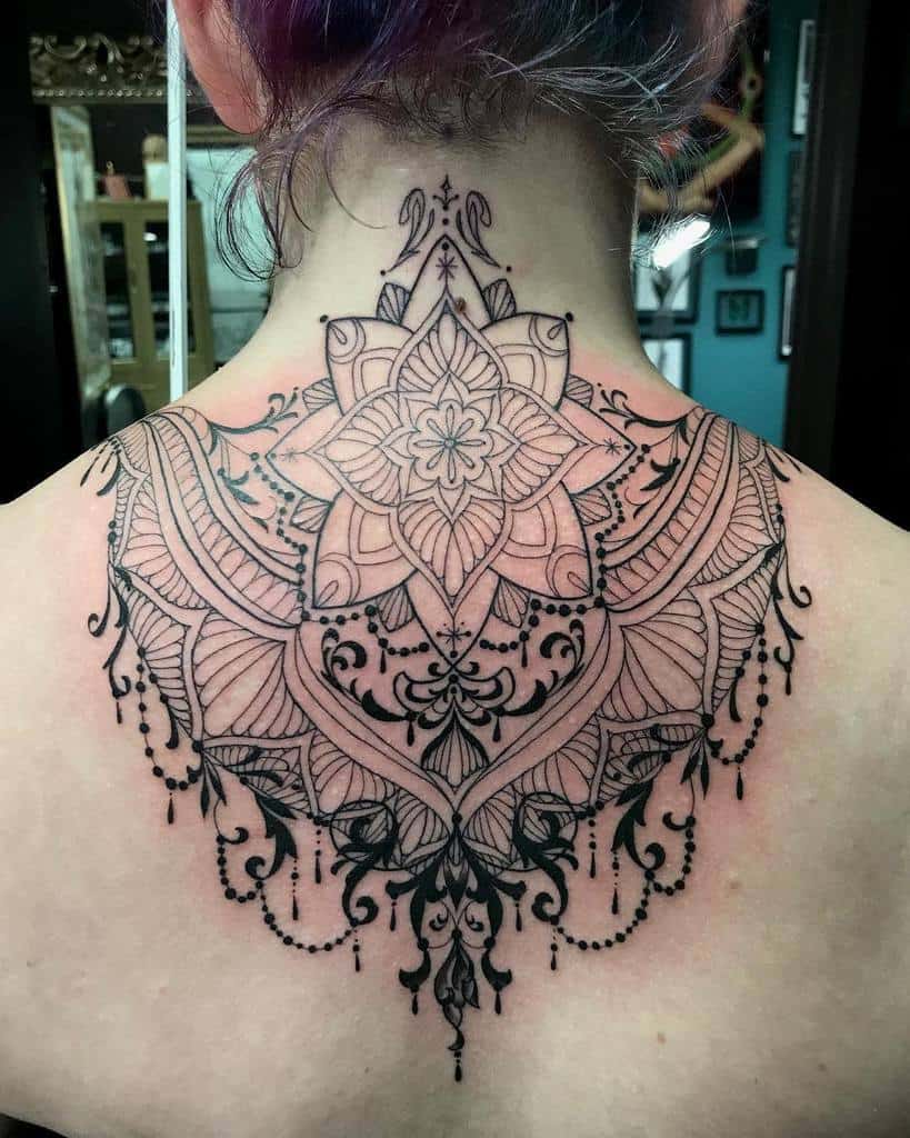 Elegant black ink tattoo featuring a mandala with intricate chandelier-style detailing and delicate hanging beads