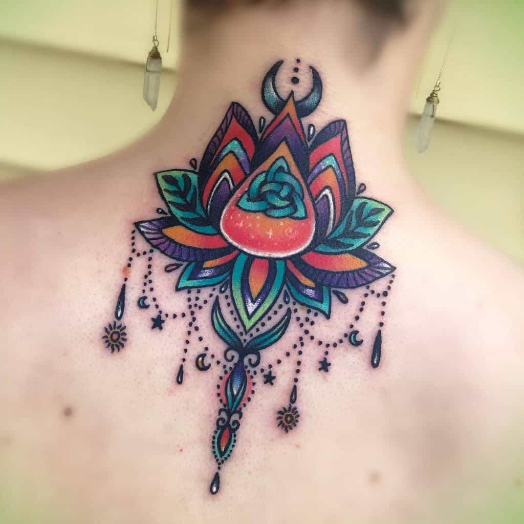 Vibrant, colorful tattoo featuring a stylized lotus flower with bold geometric patterns, a crescent moon on top, and chandelier-style beads adorned with stars, moons, and suns
