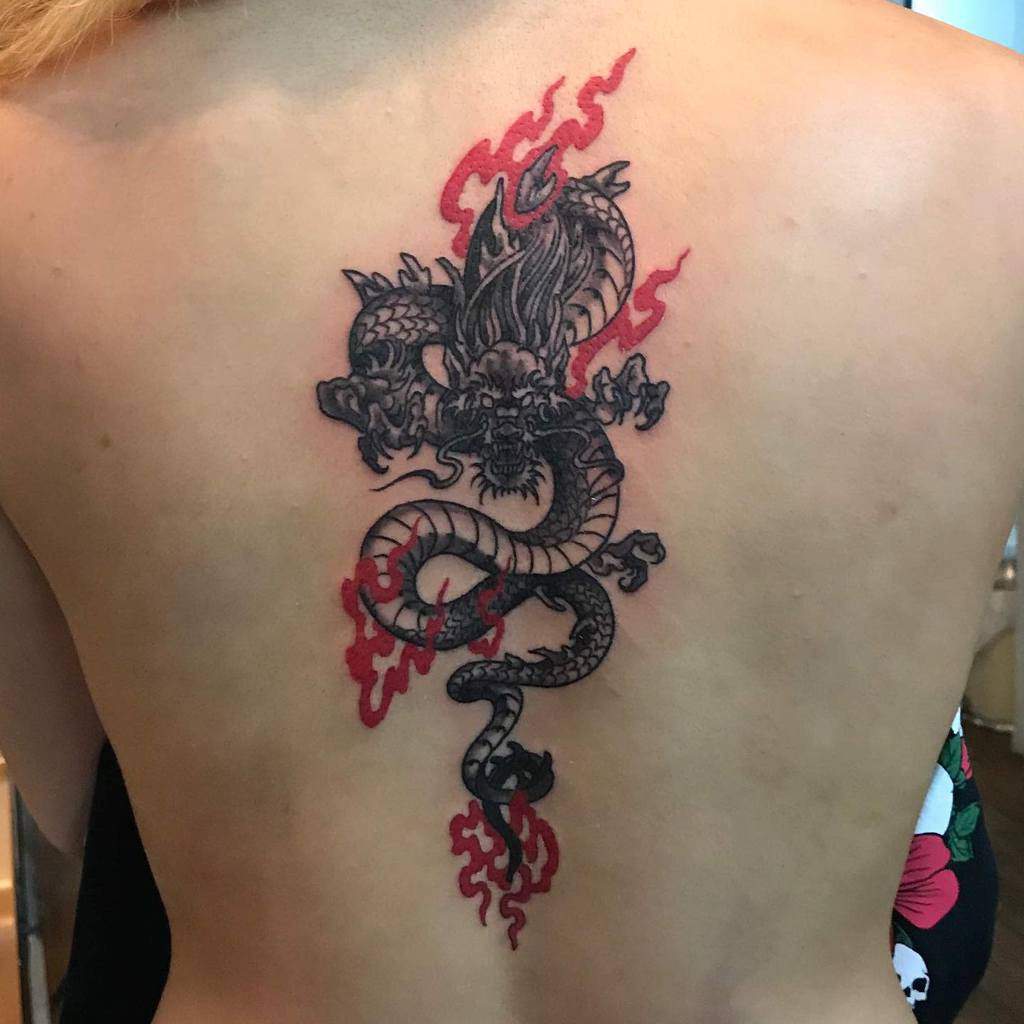 Dragon tattoo with red flames on a woman's back