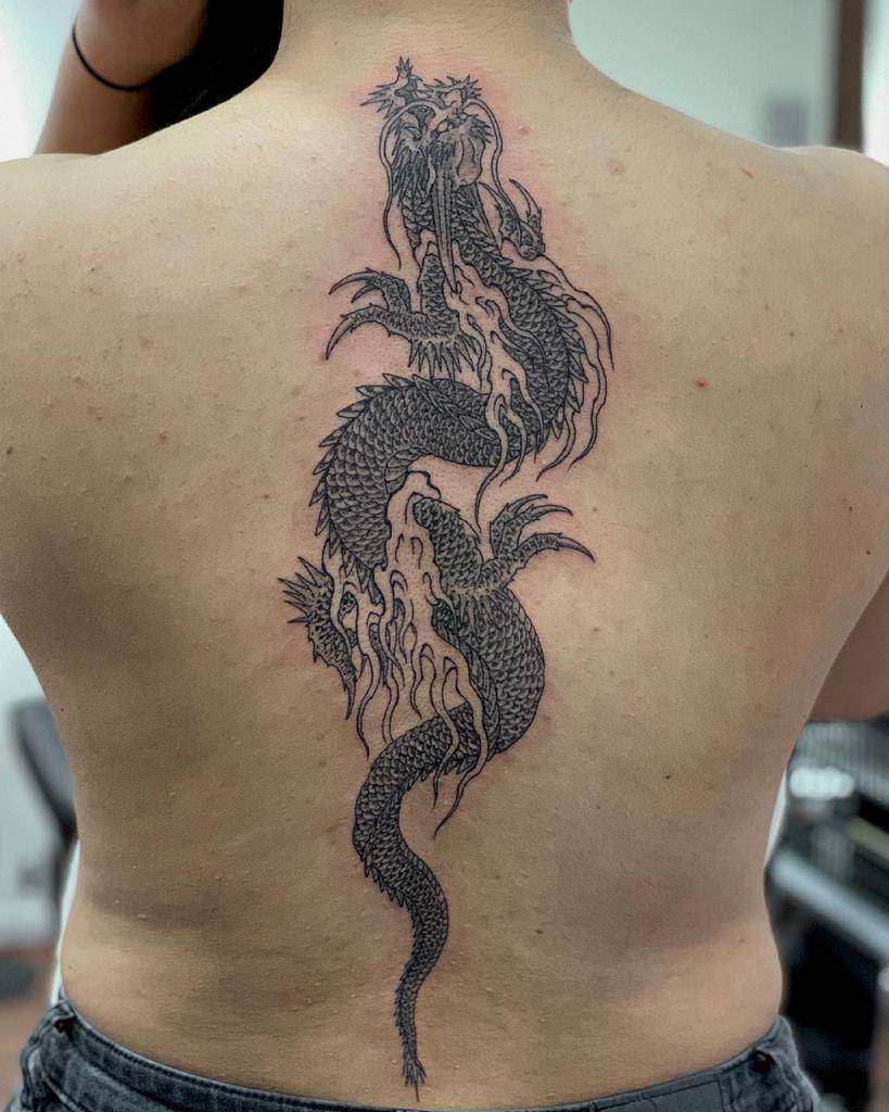 Black dragon tattoo on a woman's back, featuring intricate details and scales