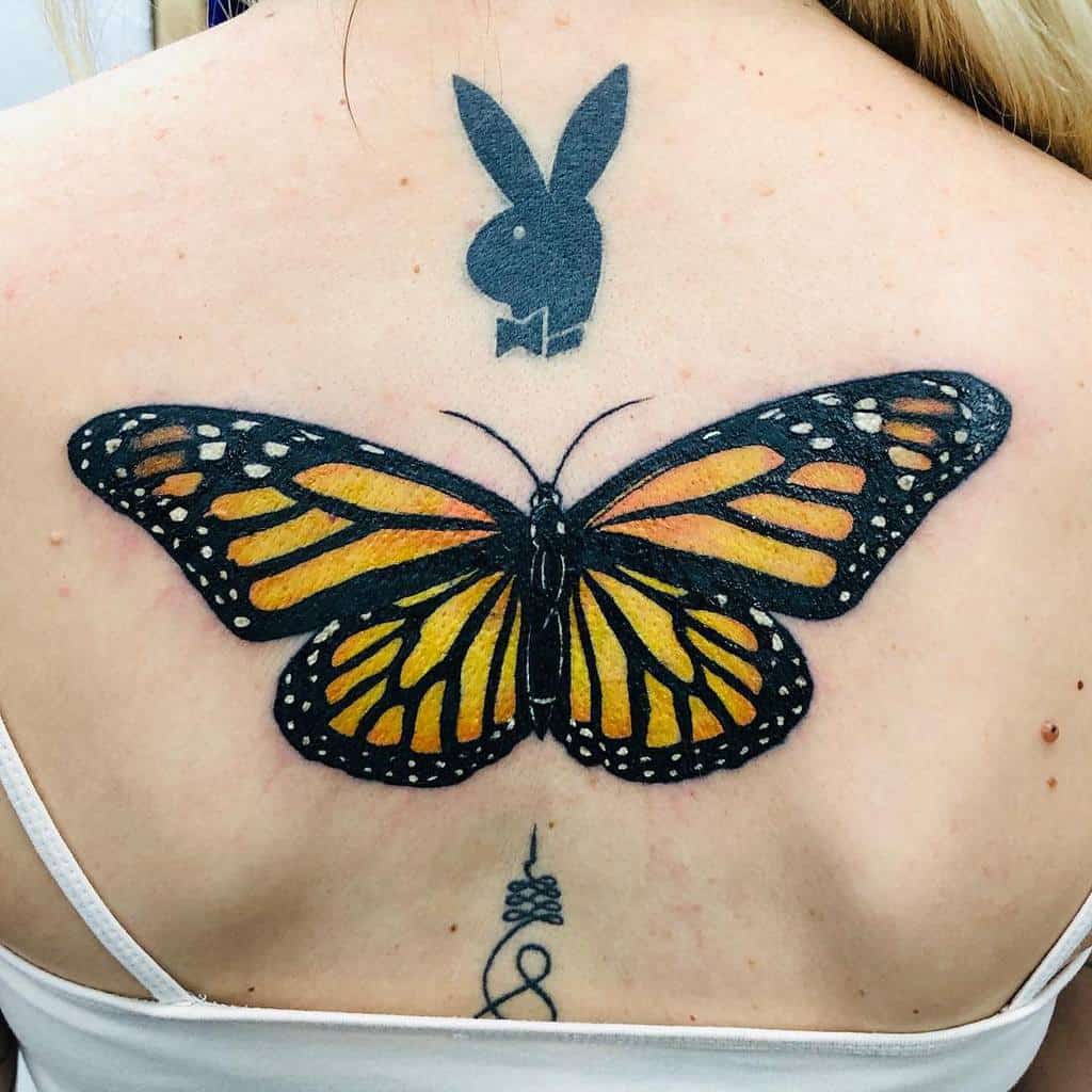 A large monarch butterfly tattoo graces the person's back