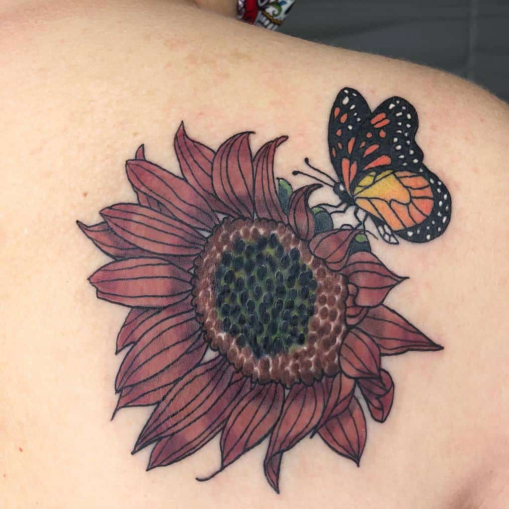 A tattoo of a red sunflower with a vibrant monarch butterfly, showcasing striking orange and black hues, adorns the shoulder