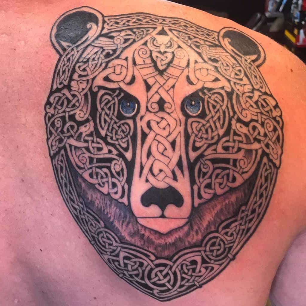 Celtic knot bear tattoo on a person's back features an intricate design and mesmerizing blue eyes, capturing the essence of its powerful spirit