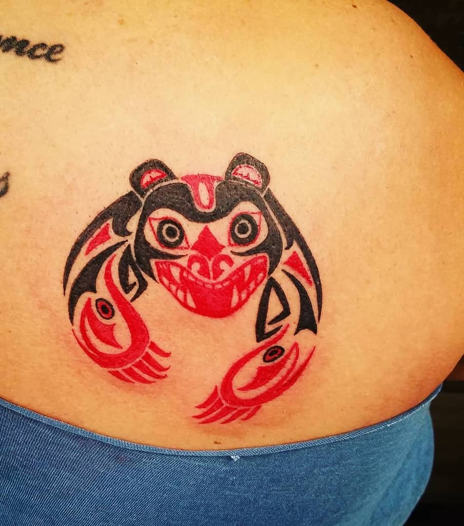 A striking tattoo of a stylized red and black bear adorns the person's shoulder