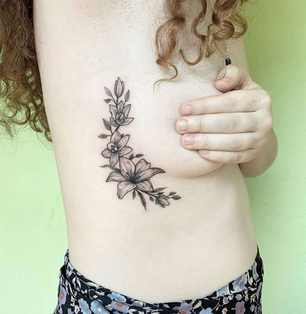 Delicate black and grey tattoo of blooming lilies and wildflowers, creating a feminine and elegant floral design along the side