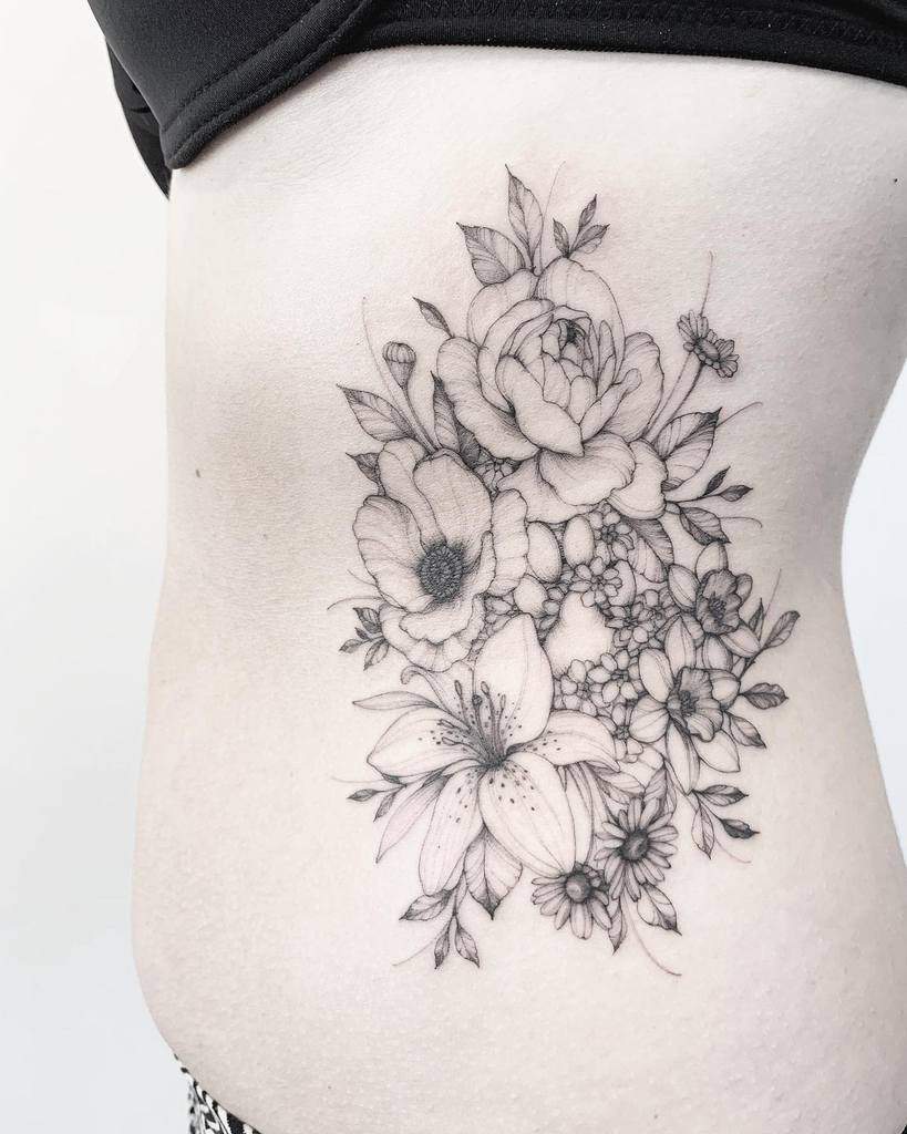 Intricate black and grey tattoo of a floral bouquet featuring a lily, roses, and wildflowers, symbolizing beauty, growth, and femininity