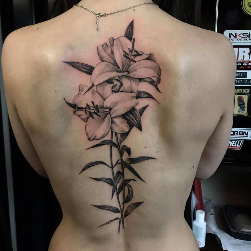 Elegant black and grey back tattoo of blooming lilies, symbolizing beauty, growth, and femininity