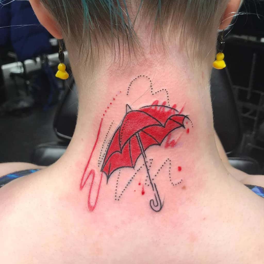 A red umbrella tattoo with dotted and abstract designs adorning the back of a neck, adding a touch of whimsy