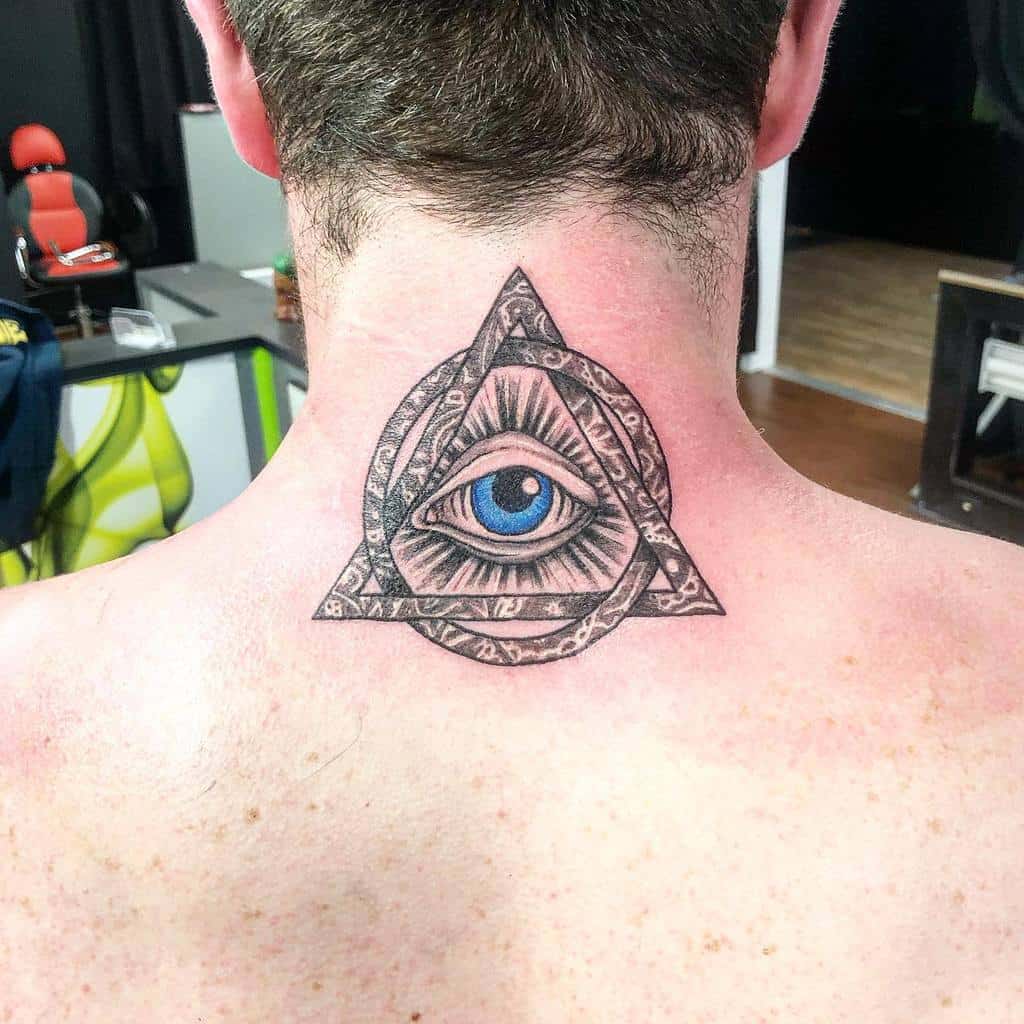 Tattoo of an all-seeing eye within a triangle with intricate designs on the back of the neck and upper back