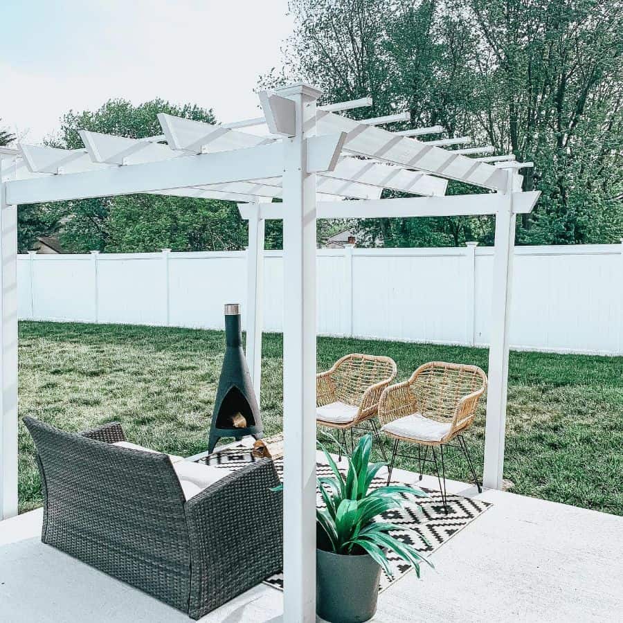 concrete patio with white pergola and wicker sofa