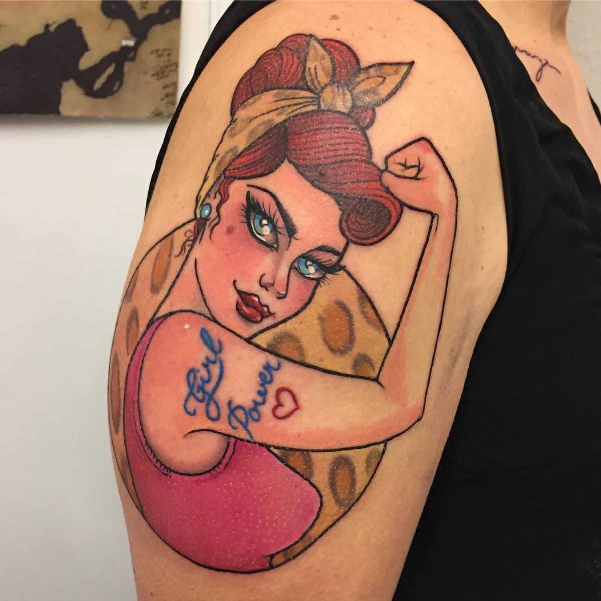 Tattoo of Rosie the Riveter on an upper arm with "Girl Power" written on her flexed bicep and wearing a polka dot scarf