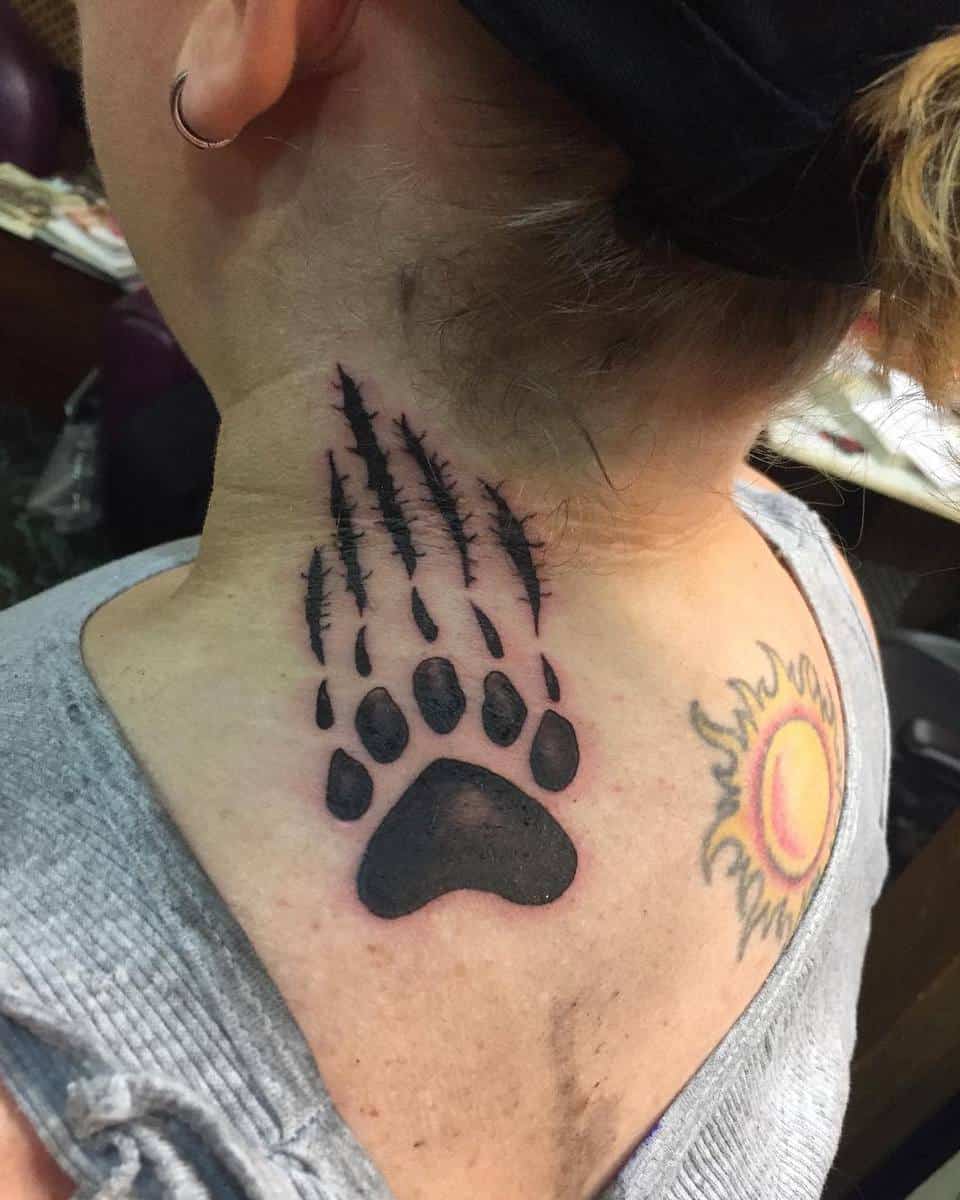 Bear paw with claw marks on neck next to a vibrant sun tattoo on shoulder