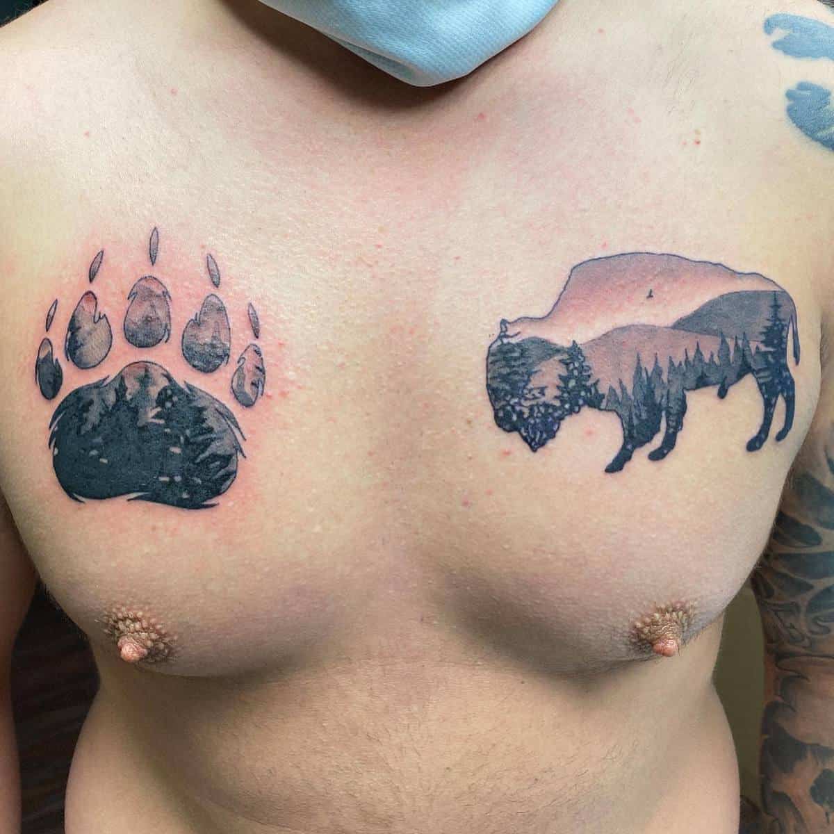 Tattooed chest with a bear paw on the left and a detailed bison with trees and mountains on the right