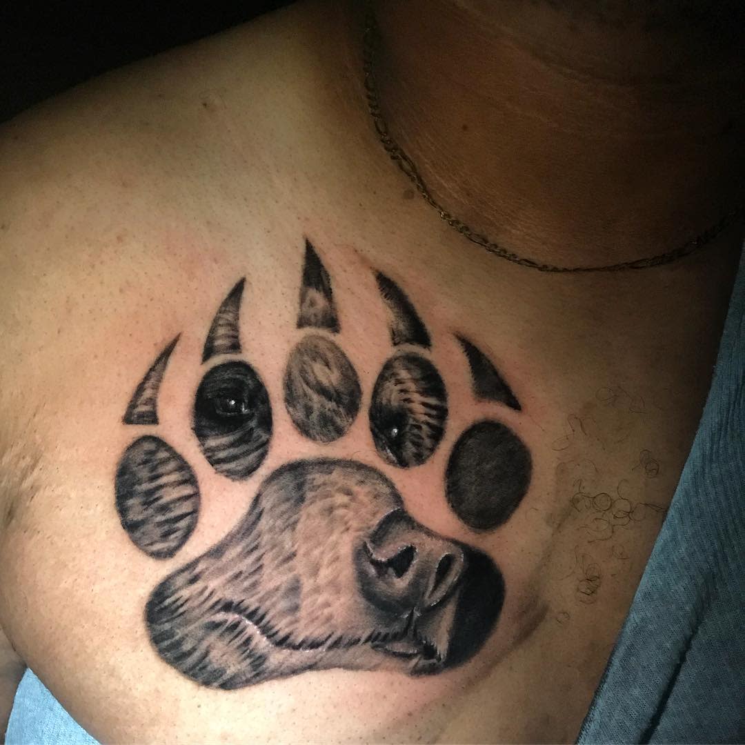 Tattoo of a bear paw print with a bear's face inside on a person's chest
