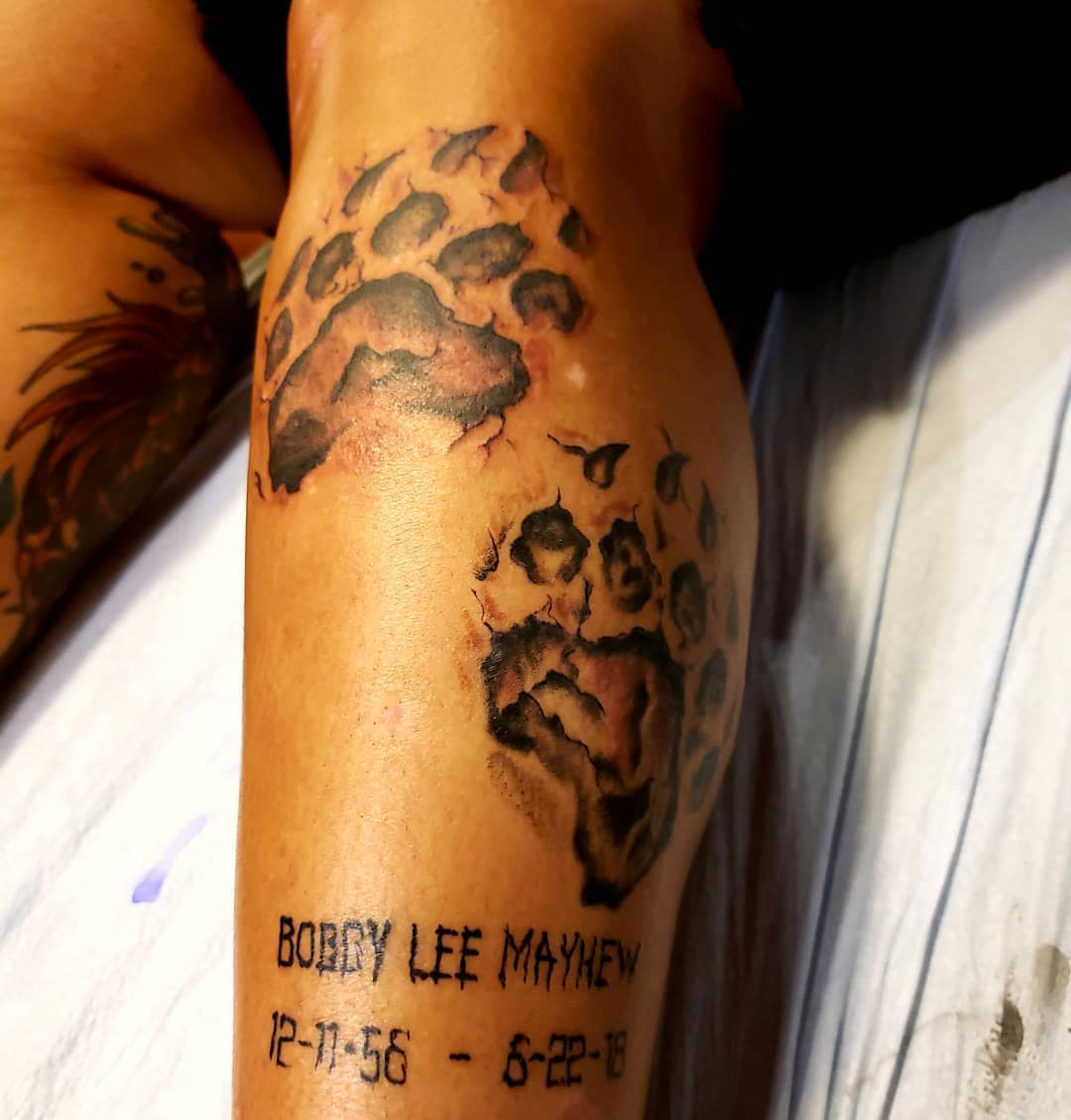 Tattoo of bear paw prints and text "Bobby Lee Mayhew 12-11-56 - 6-28-18" on someone's arm