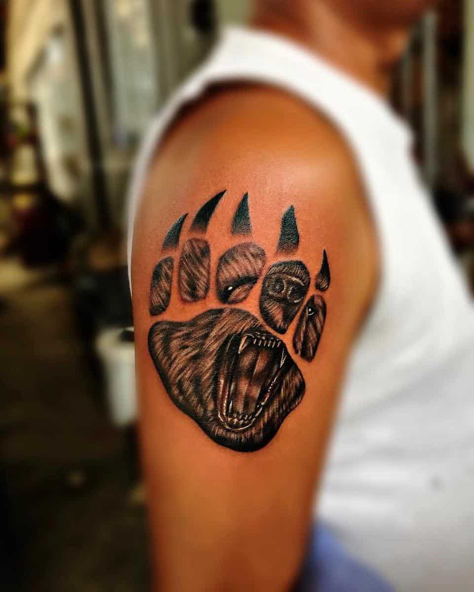 Tattoo of a bear paw and face on upper arm