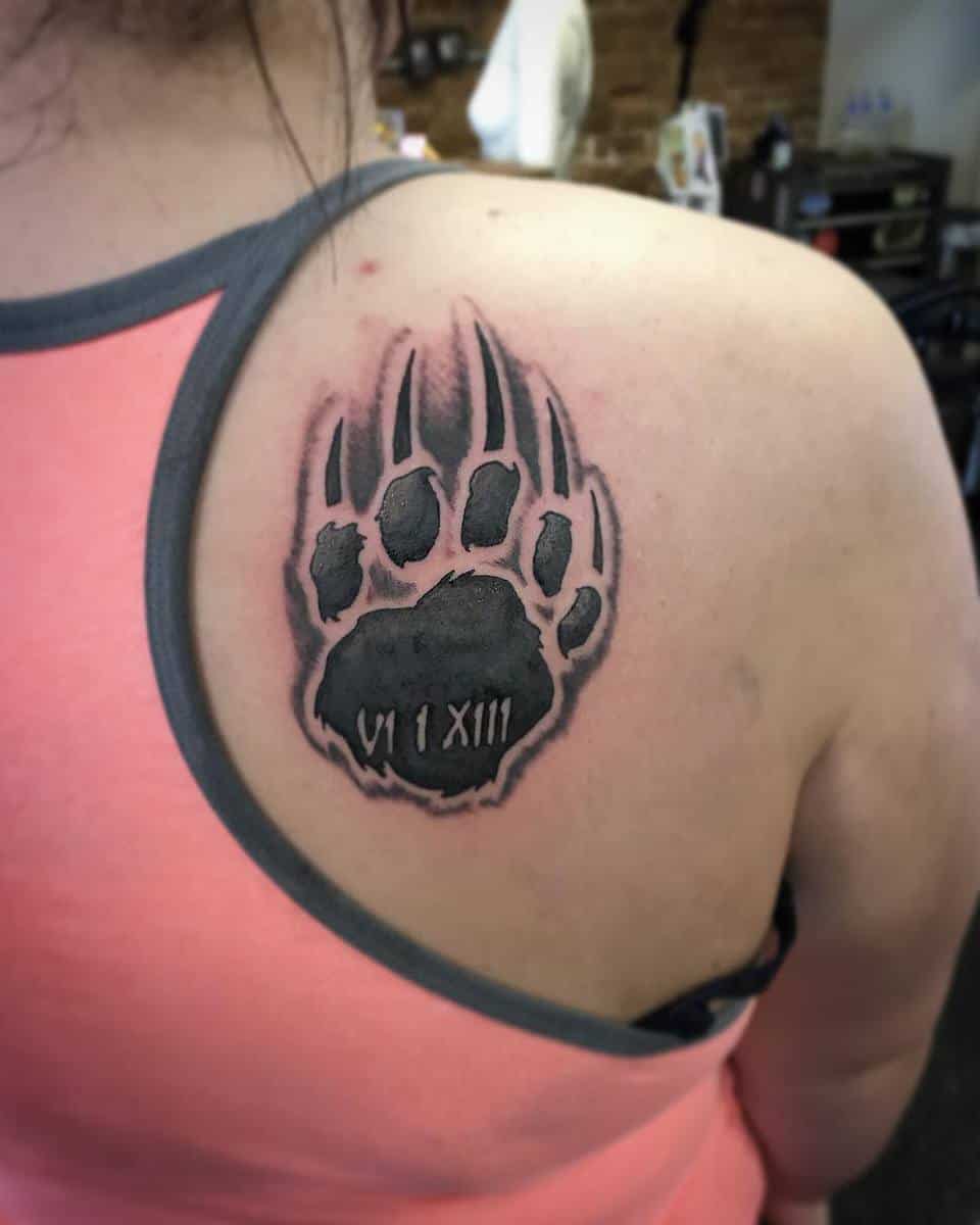 Bear paw tattoo with Roman numerals on upper back