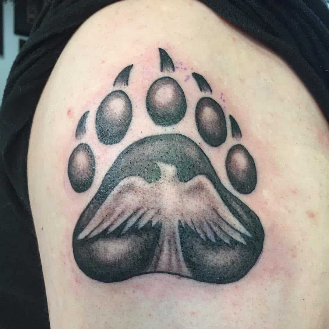Tattoo of a bear paw with an eagle in the middle, on a person's shoulder