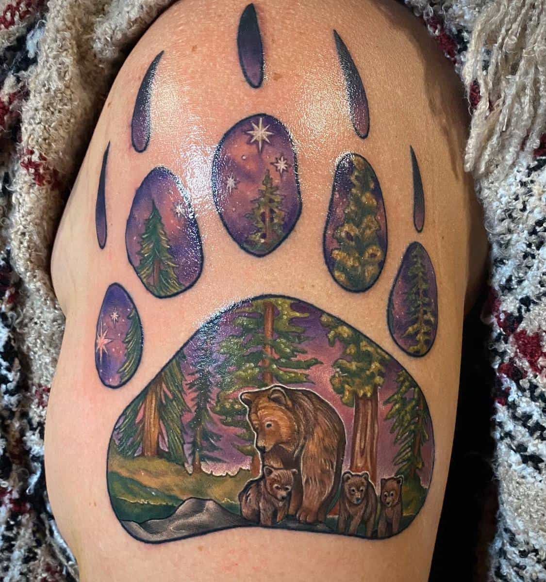 A stunning tattoo of a bear with cubs in a forest, all expertly framed within the outline of a bear paw print