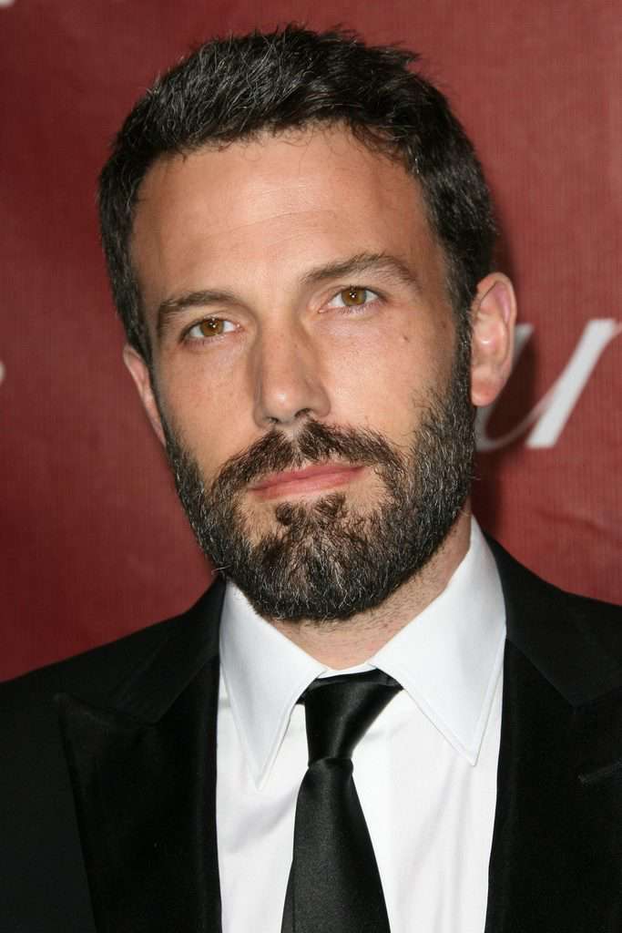 A picture of Ben Affleck in his suit tie and has beard on his face