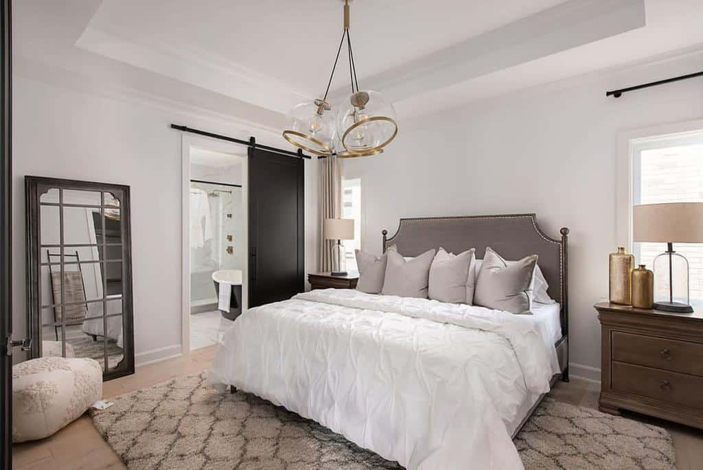 Modern bedroom with ensuite bathroom, sliding barn door, and brown cabinets.