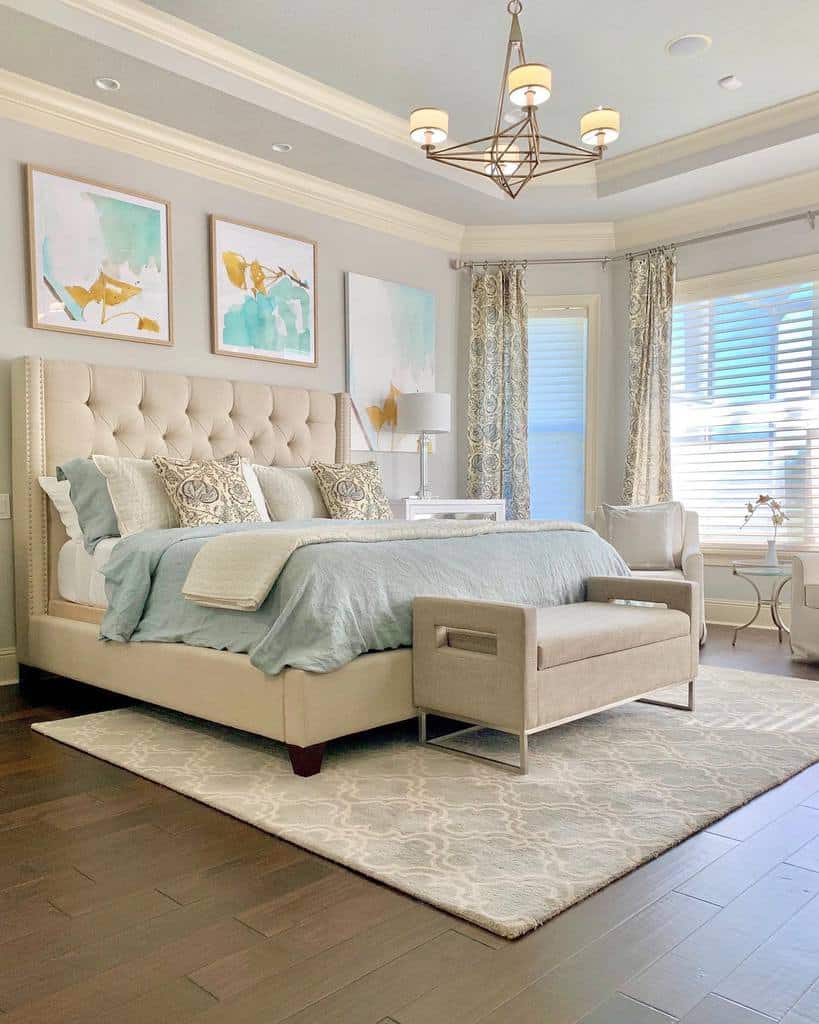 Elegant bedroom with tufted bed canvas wall art geometric chandelier and patterned gray rug.