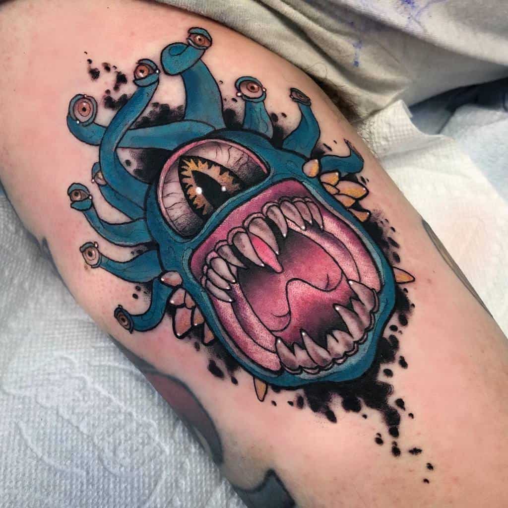 Bright teal Beholder tattoo with a menacing grin and multiple glowing eyes, detailed with vibrant shading and splatter effects