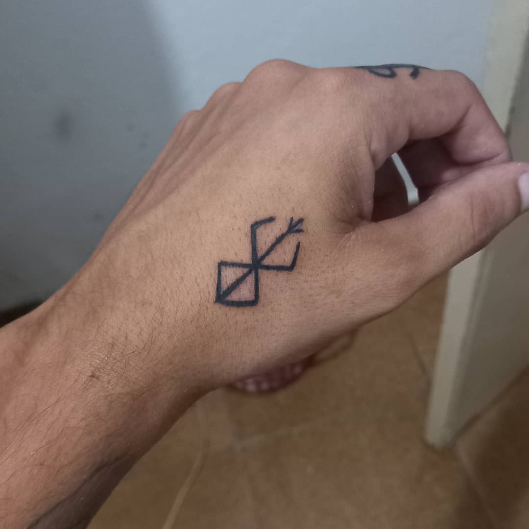 Minimalist tattoo of the Brand of Sacrifice from Berserk, placed on the hand in simple black ink