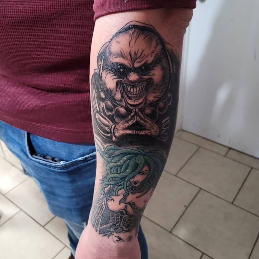 Forearm tattoo featuring the God Hand member Void and Slan from Berserk, depicted with dark, intense shading