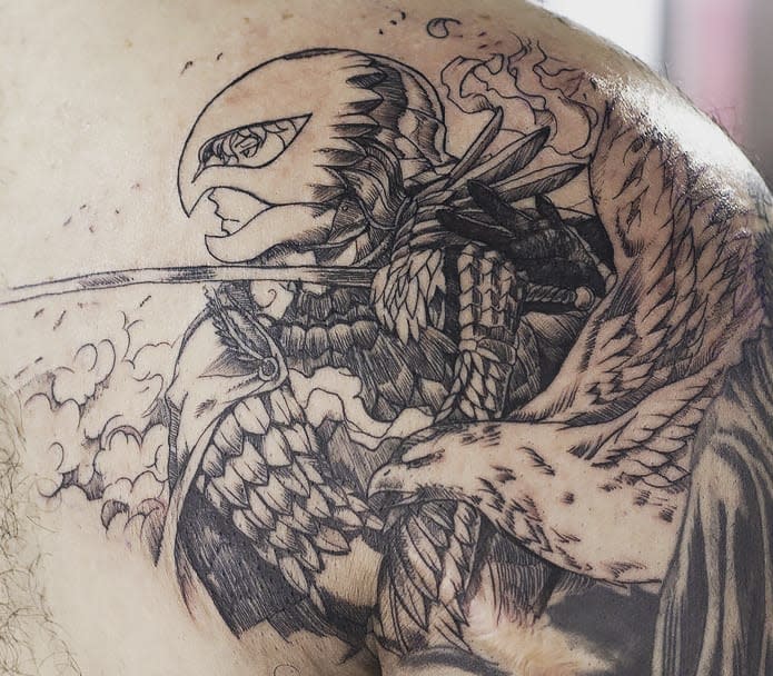 Intricate tattoo of Griffith from Berserk in his Hawk of Light armor, with detailed feathers and a fierce expression, set against a cloudy background