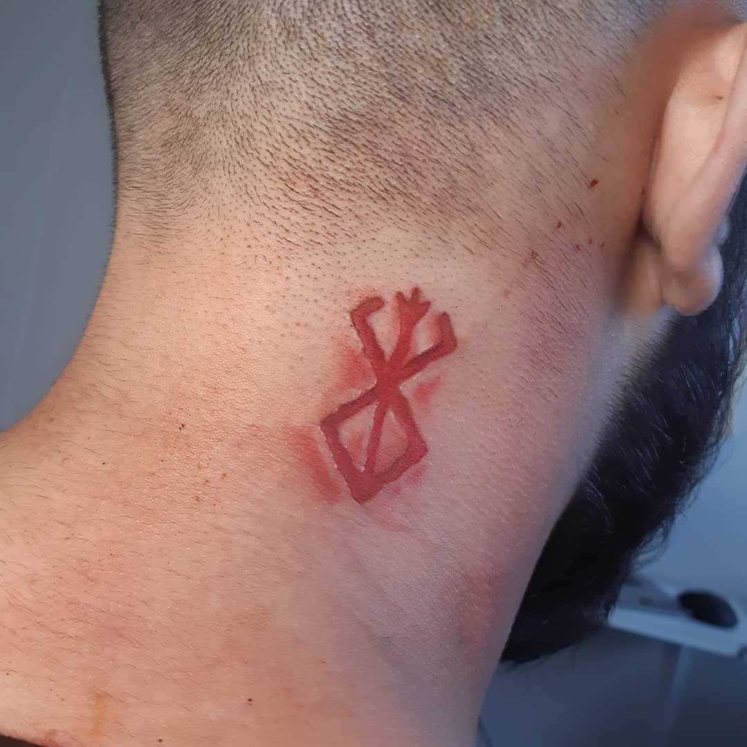 Minimalist tattoo of the Brand of Sacrifice from Berserk on the side of the neck, depicted in a subtle red ink with a slightly raw effect
