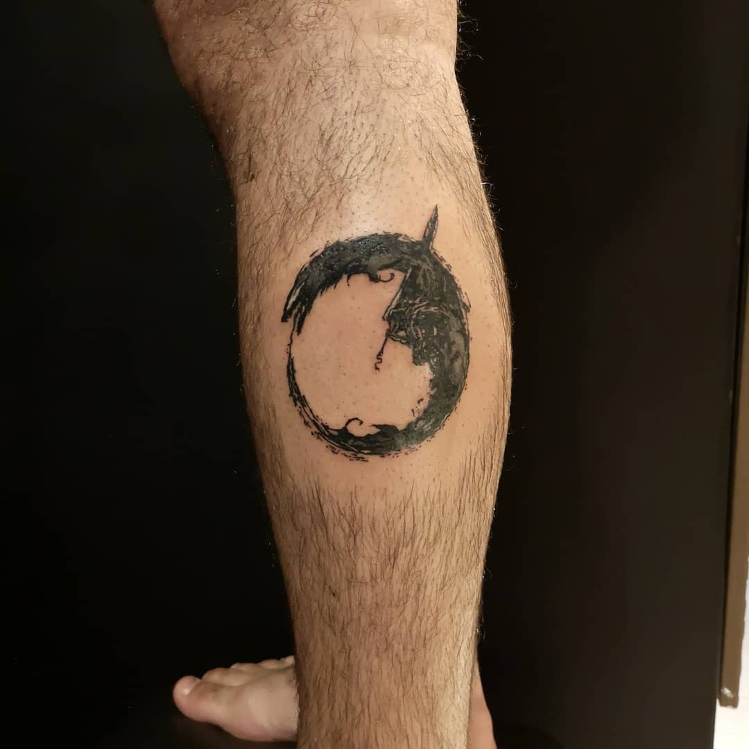 Minimalist tattoo of the Berserk Beast of Darkness on the calf, depicted in a circular, brushstroke style, symbolizing the inner struggle of Guts