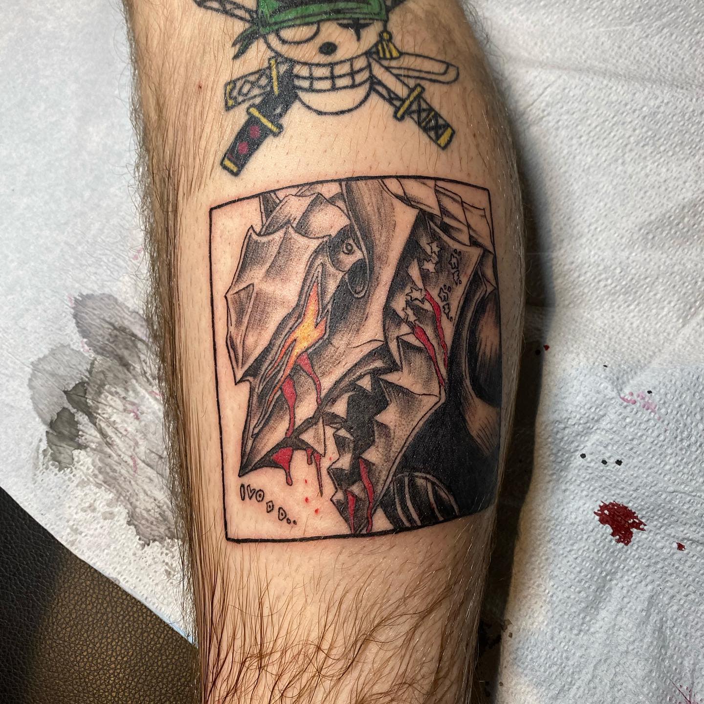 Tattoo of the Berserk Armor's wolf-like form on the leg, depicted with intense shading, sharp teeth, and dripping blood, framed within a rectangular border for a panel-like effect