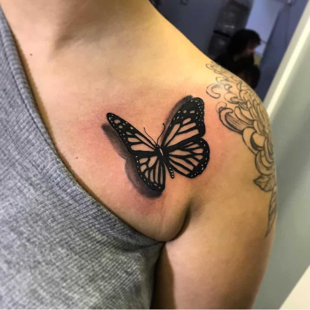 A monochrome butterfly tattoo near a collarbone