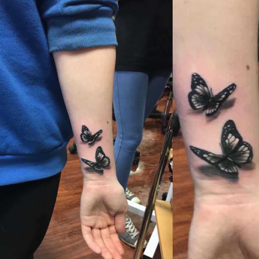 Forearm tattoo of two black and grey butterflies