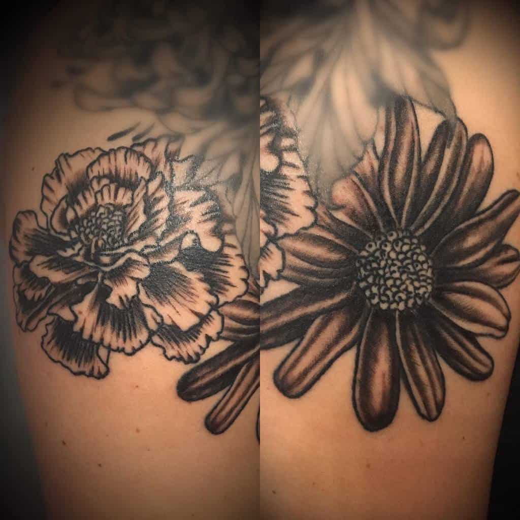 Black and white tattoo of two large aster flowers on the upper arm