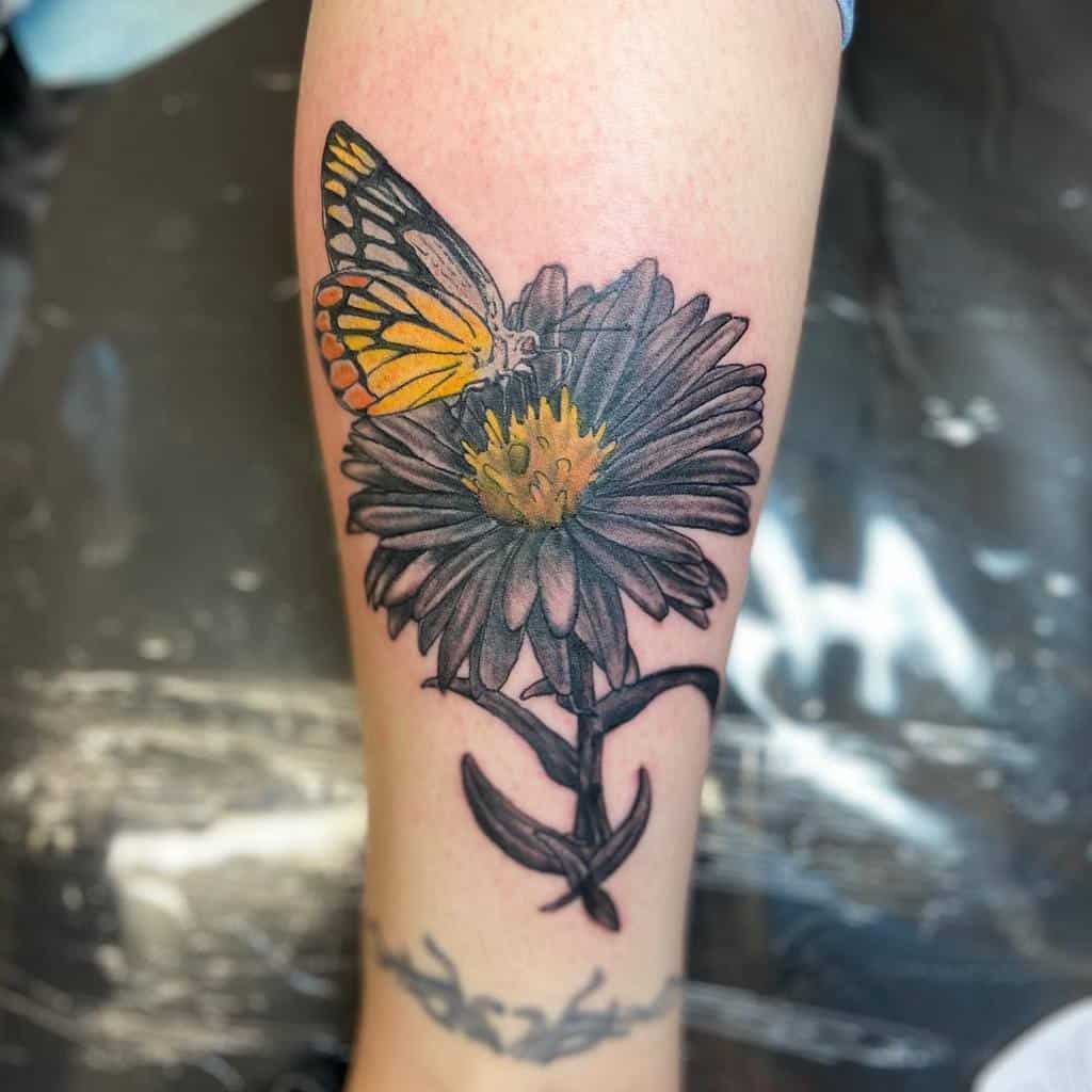Tattoo of a butterfly landing on an aster situated on a person's forearm