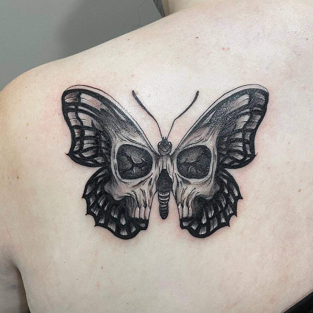 A striking black butterfly tattoo with skulls intricately woven into its wings graces a person's upper back