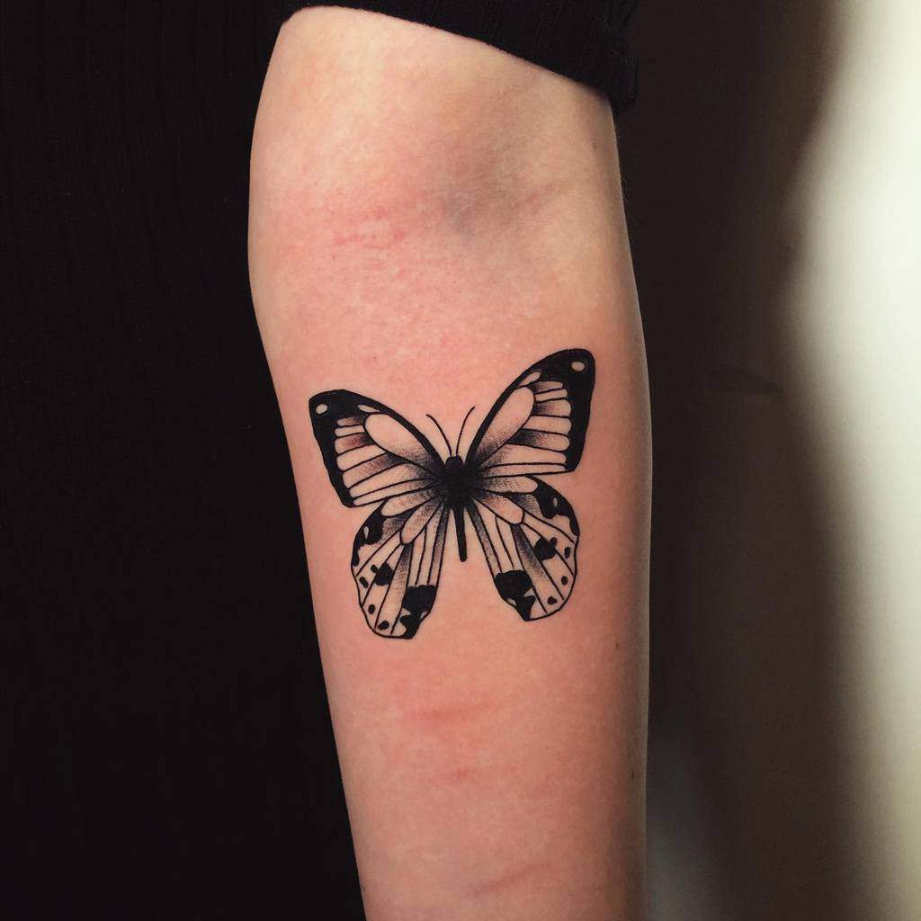 Black ink black butterfly tattoo on the inner side of an arm