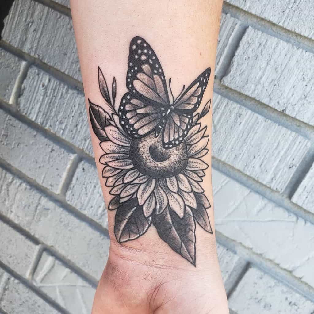 Beautiful black and grey butterfly and sunflower tattoo on the forearm, blending nature and elegance with intricate shading.