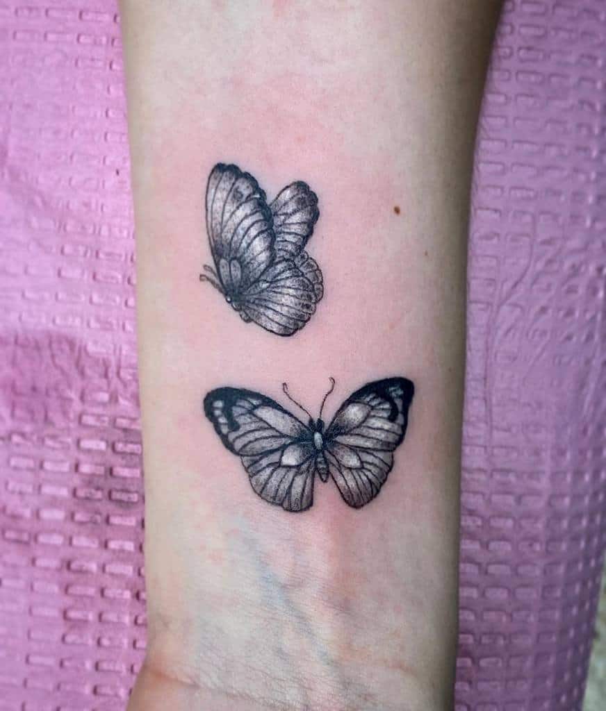 Delicate black and grey butterfly tattoo on the wrist with fine details, symbolizing transformation and freedom.