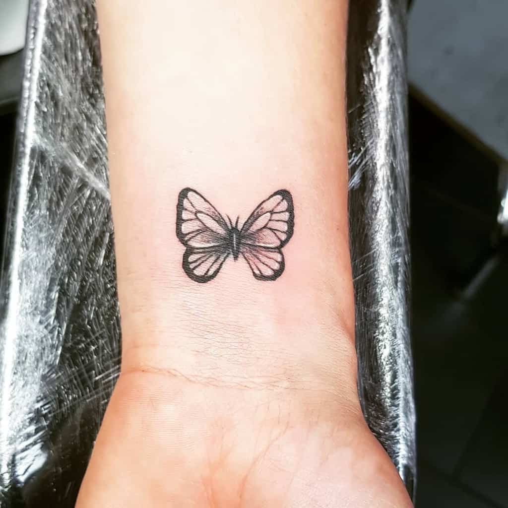 A small black butterfly tattoo on a an inner wrist