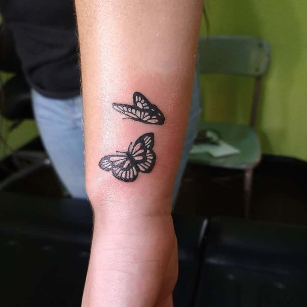 Wrist tattoo featuring two intricate black butterflies, beautifully designed