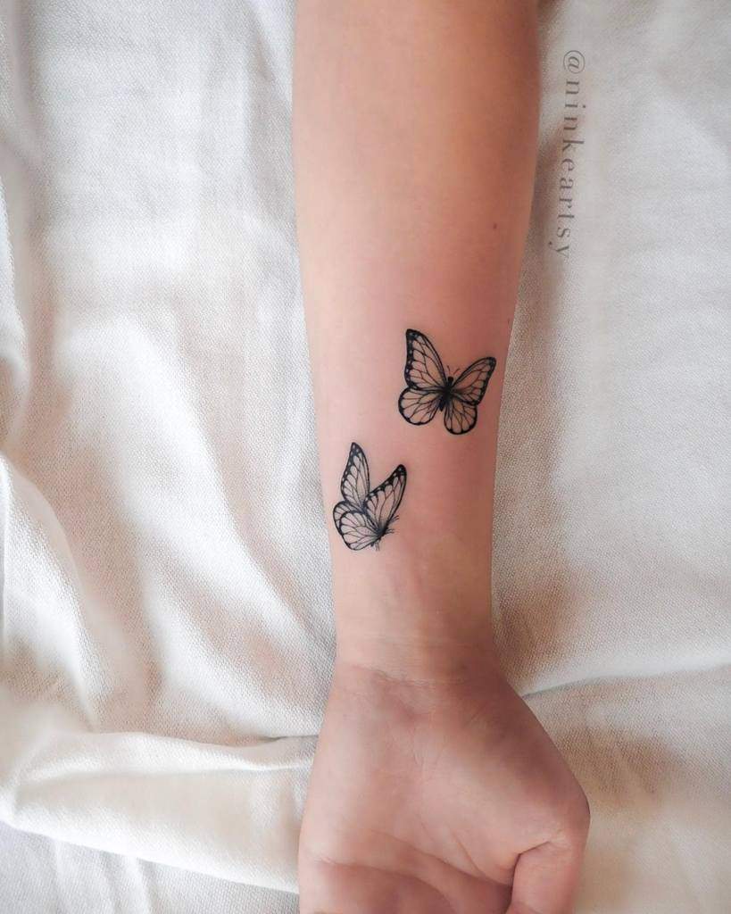 Two black butterfly tattoos on a wrist
