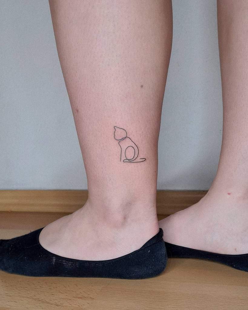 Outline tattoo of a sitting cat on the back of a person's calf
