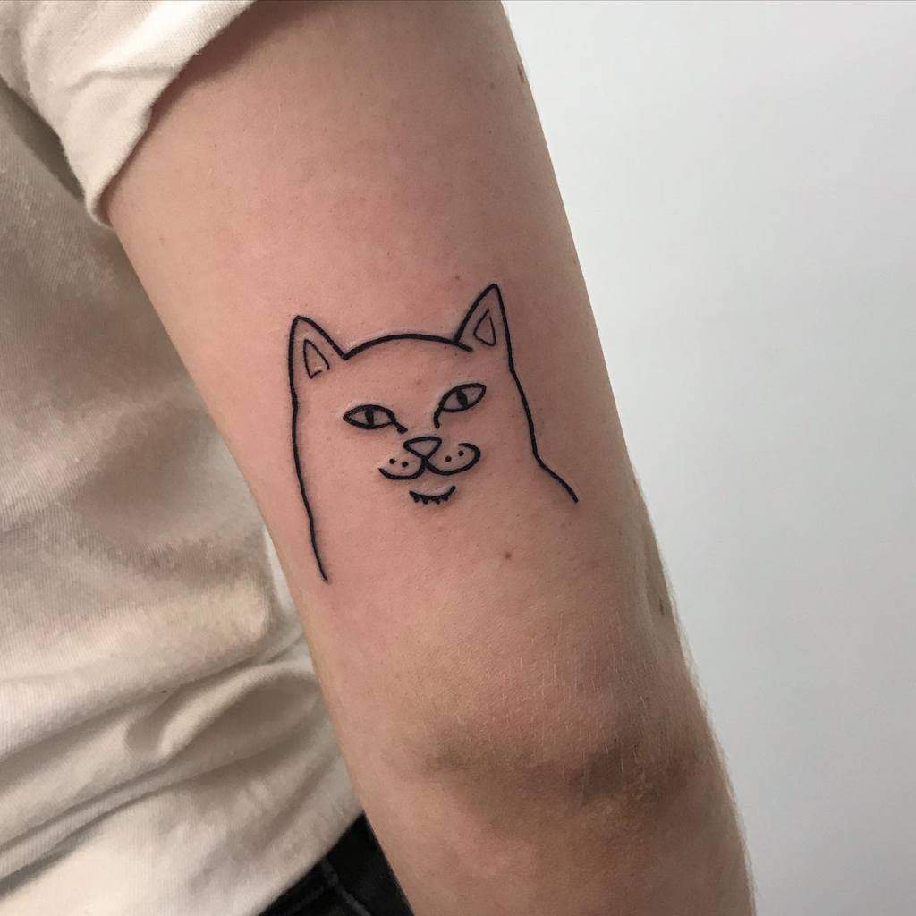 A delicate black outline tattoo of a cat's face on the inner arm of a person, perfectly capturing the essence of our beloved feline companions
