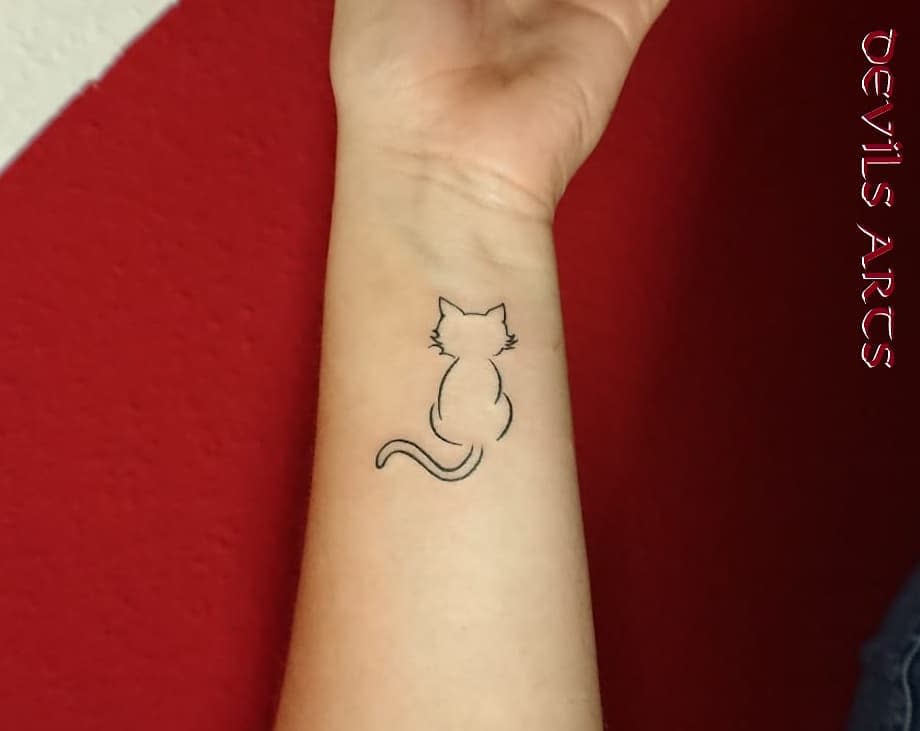 Minimalist tattoo of a cat outline on a wrist