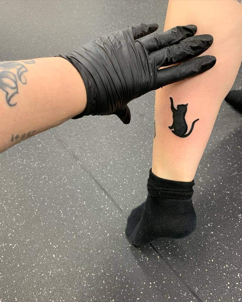 Seek black cat tattoo on a leg