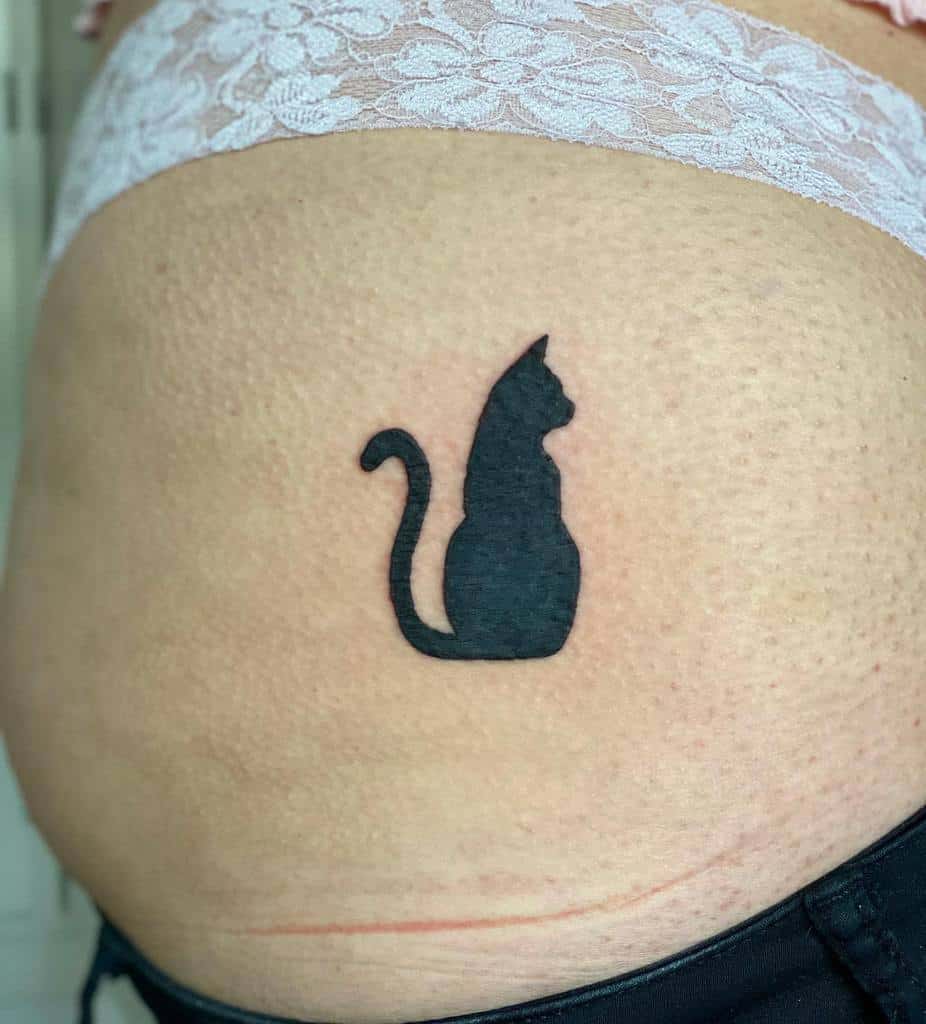 A tattoo featuring the graceful silhouette of a black cat adorns the side of a person's torso, nestled near the waist